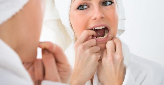 40369161 - close-up of a woman looking in mirror flossing teeth